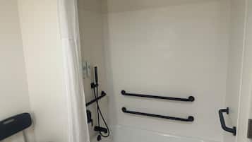 Un bagno con una vasca da bagno bianca, una zona doccia e una sedia con un asciugamano.