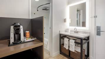 A modern bathroom with a shower, a coffee machine, and a sink.