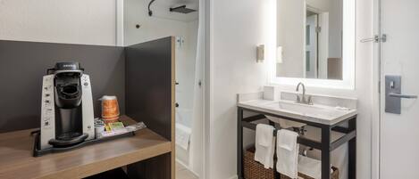 A modern bathroom with a shower, a coffee machine, and a sink.