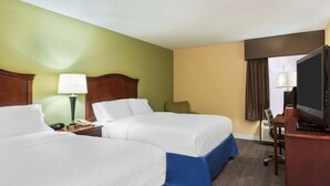 A hotel room with two beds, a desk with a computer, and a television.