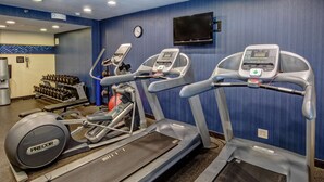 A gym with treadmills, ellipticals, and dumbbells.