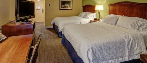 A hotel room with two beds, a TV, and a desk.