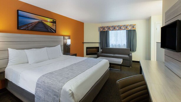 Une chambre d’hôtel avec un grand lit, un canapé, une télévision et une cheminée.
