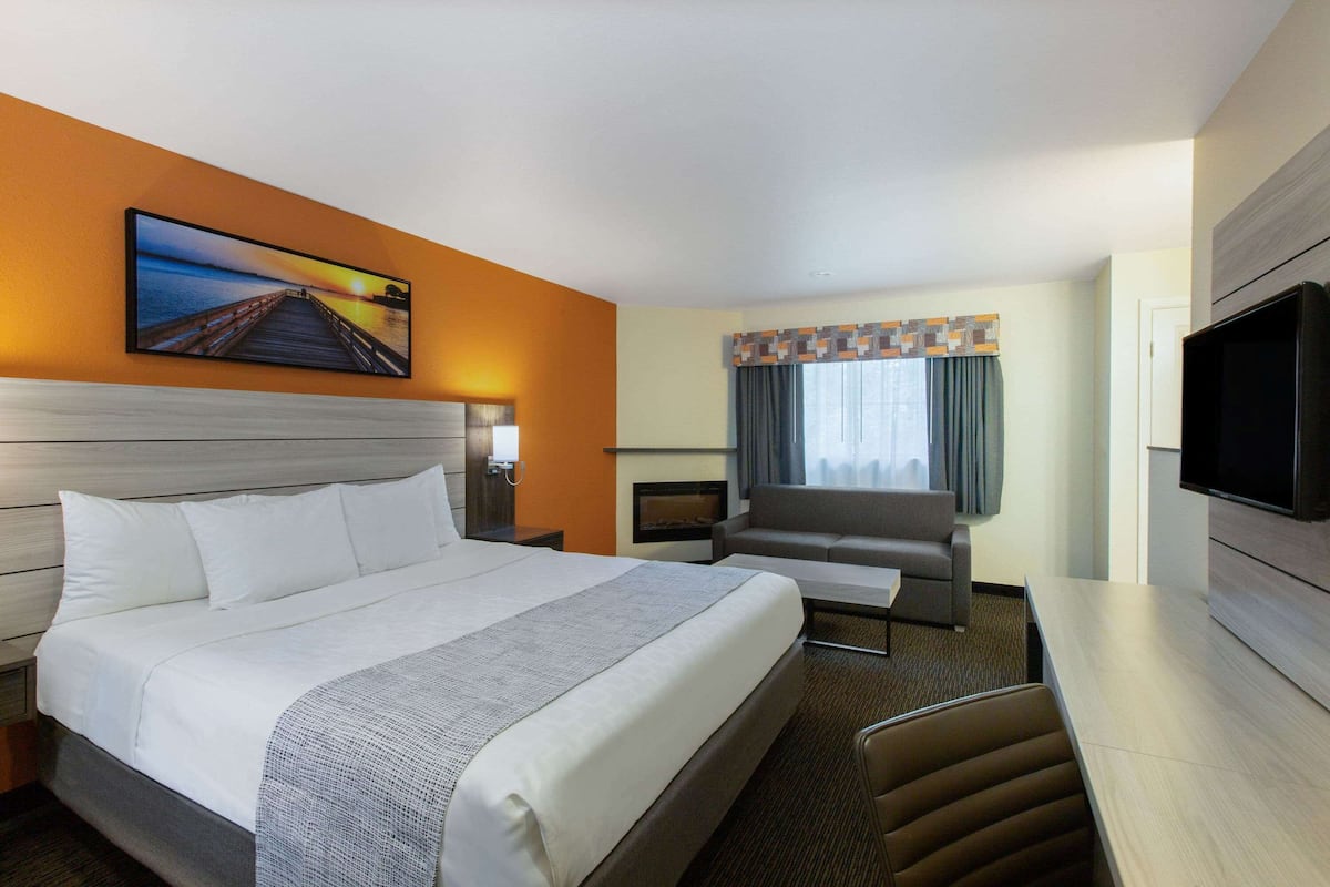 Una habitación de hotel con una cama grande, un sofá, un televisor y una chimenea.