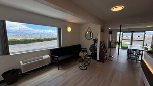 En hotelllobby med en soffa, ett litet bord med en vas, en spegel och utsikt över parkeringsplatsen.