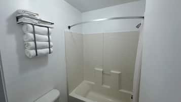 A bathroom with a white bathtub, a shower, and a towel rack with folded towels.