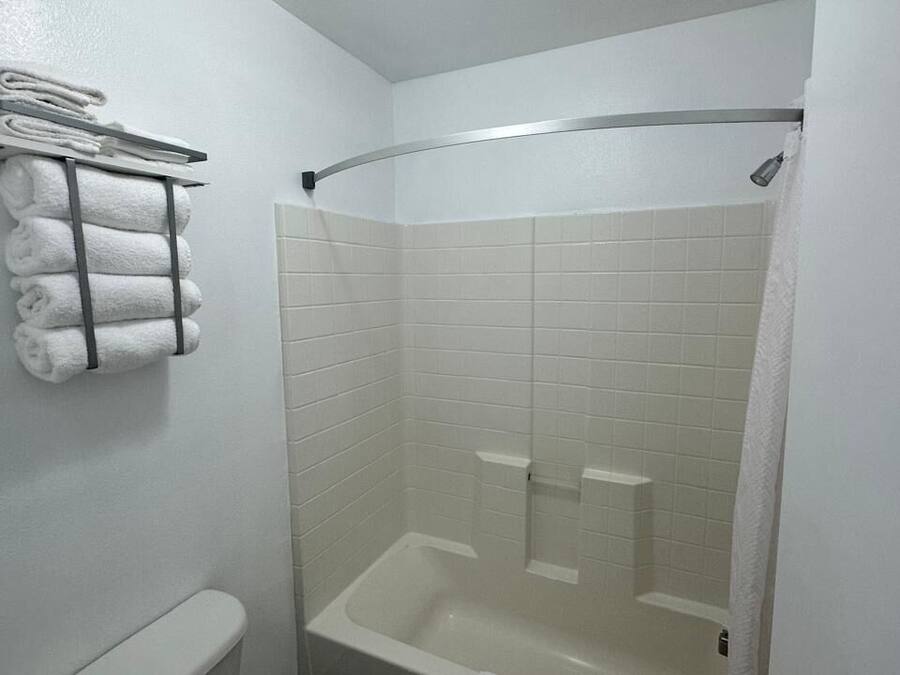 A bathroom with a white bathtub, a shower, and a towel rack with folded towels.