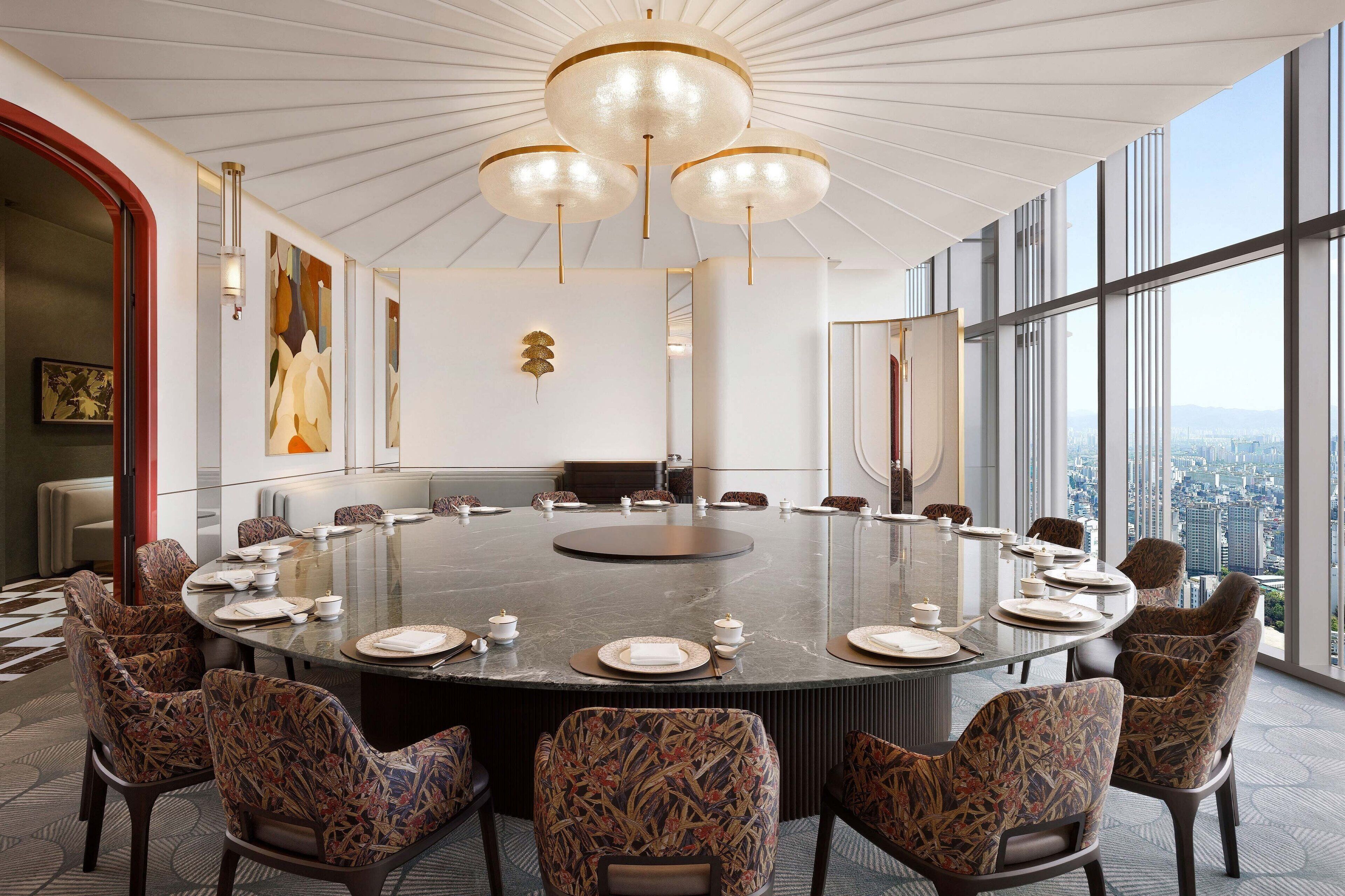 A conference room with a round table, chairs, and a city view.