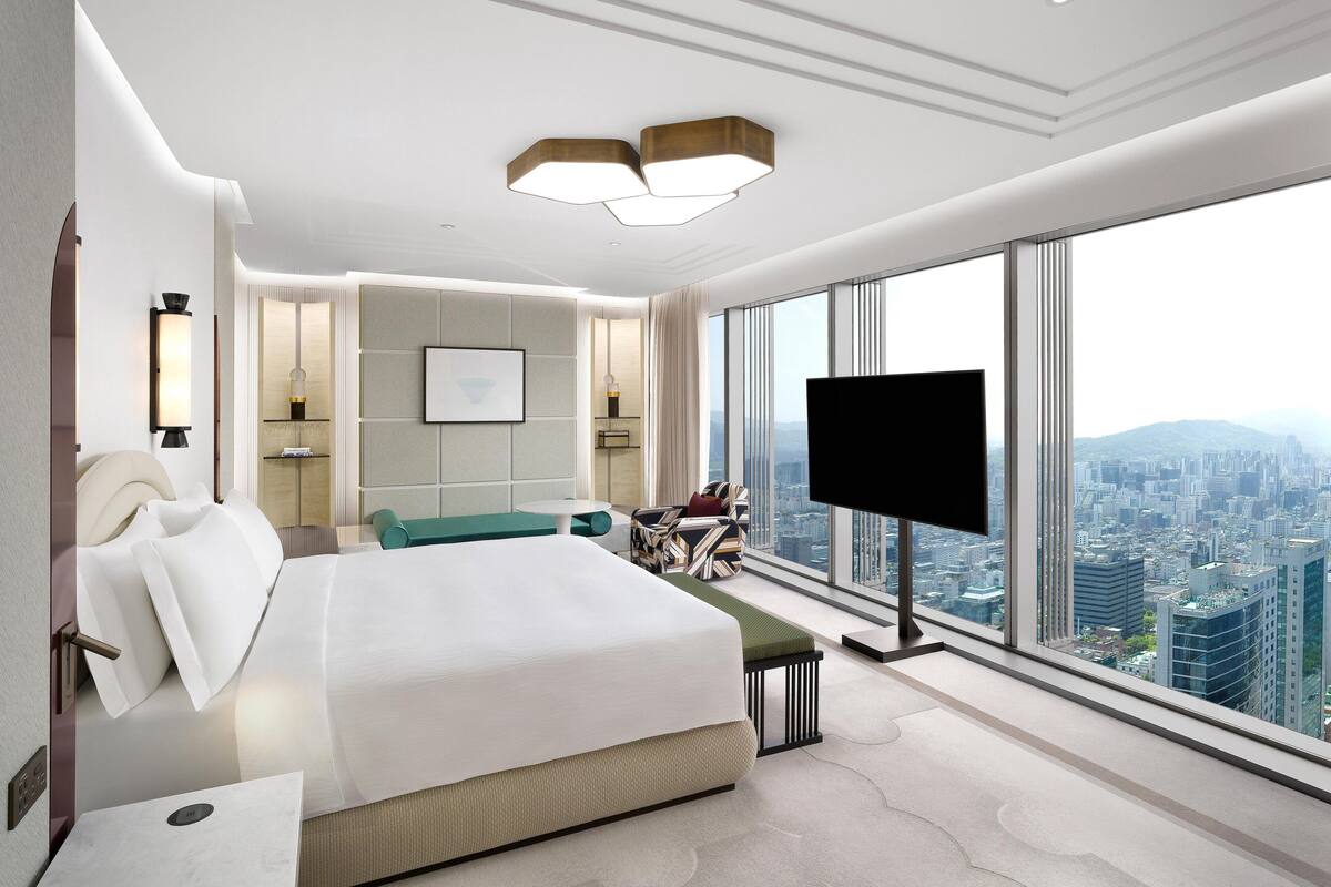 Una habitación de hotel moderna con una cama grande, televisión y vistas a la ciudad.