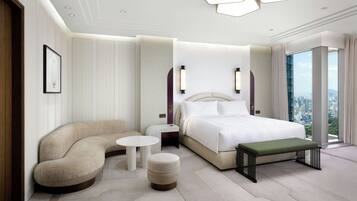 Une chambre d’hôtel moderne avec un canapé incurvé, un lit, une petite table et un banc.