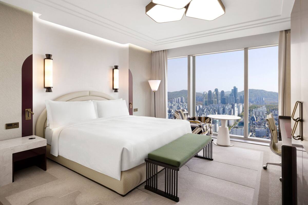 Una habitación de hotel moderna con una cama grande, un escritorio y vistas a la ciudad.
