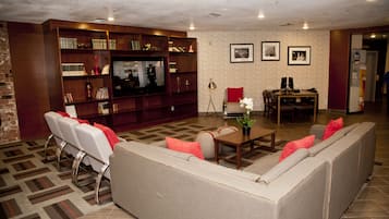 A living room with a large flat-screen TV, a sofa, a coffee table, and a bookshelf.