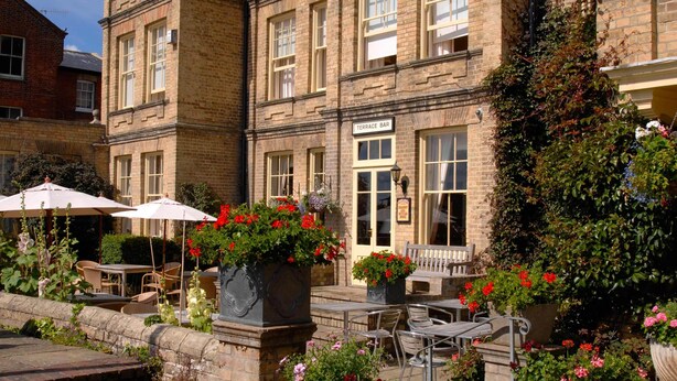 A terrace bar with outdoor seating, surrounded by brick buildings and potted plants. - Wentworth Hotel (Aldeburgh)