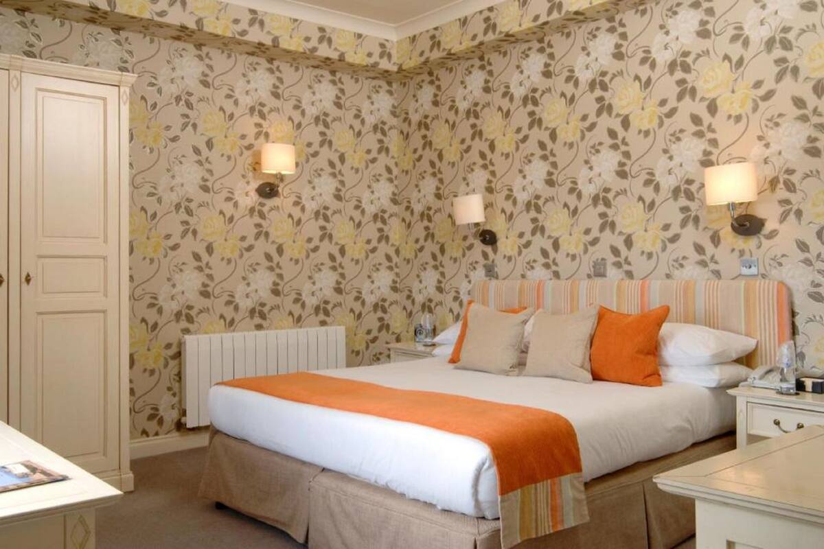 A hotel room with a bed, a nightstand, a radiator, and a door.