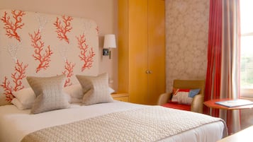 Une chambre d’hôtel avec un grand lit, une armoire, une table de chevet et une fenêtre avec des rideaux.