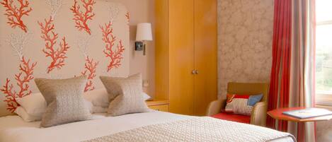 A hotel room with a large bed, a wardrobe, a bedside table, and a window with curtains.