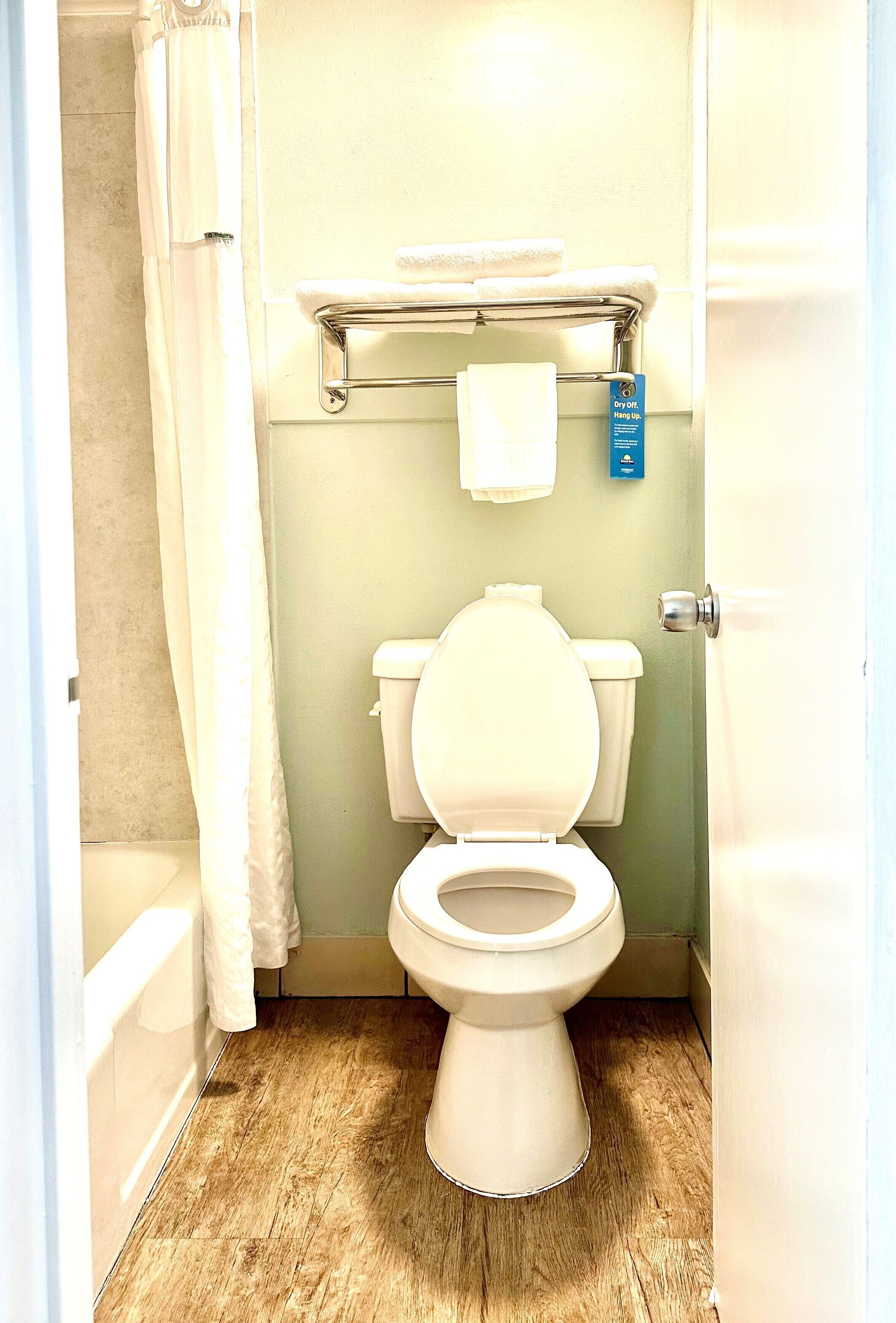 A small bathroom with a toilet, a towel rack, and a shower curtain.