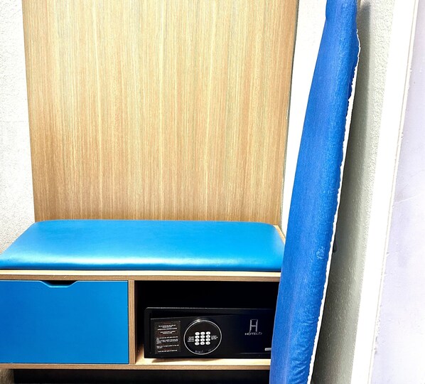 Un mur recouvert de panneaux de bois, agrémenté d’un banc bleu rembourré et d’un appareil électronique noir, qui pourrait être un thermostat ou un panneau de commande.