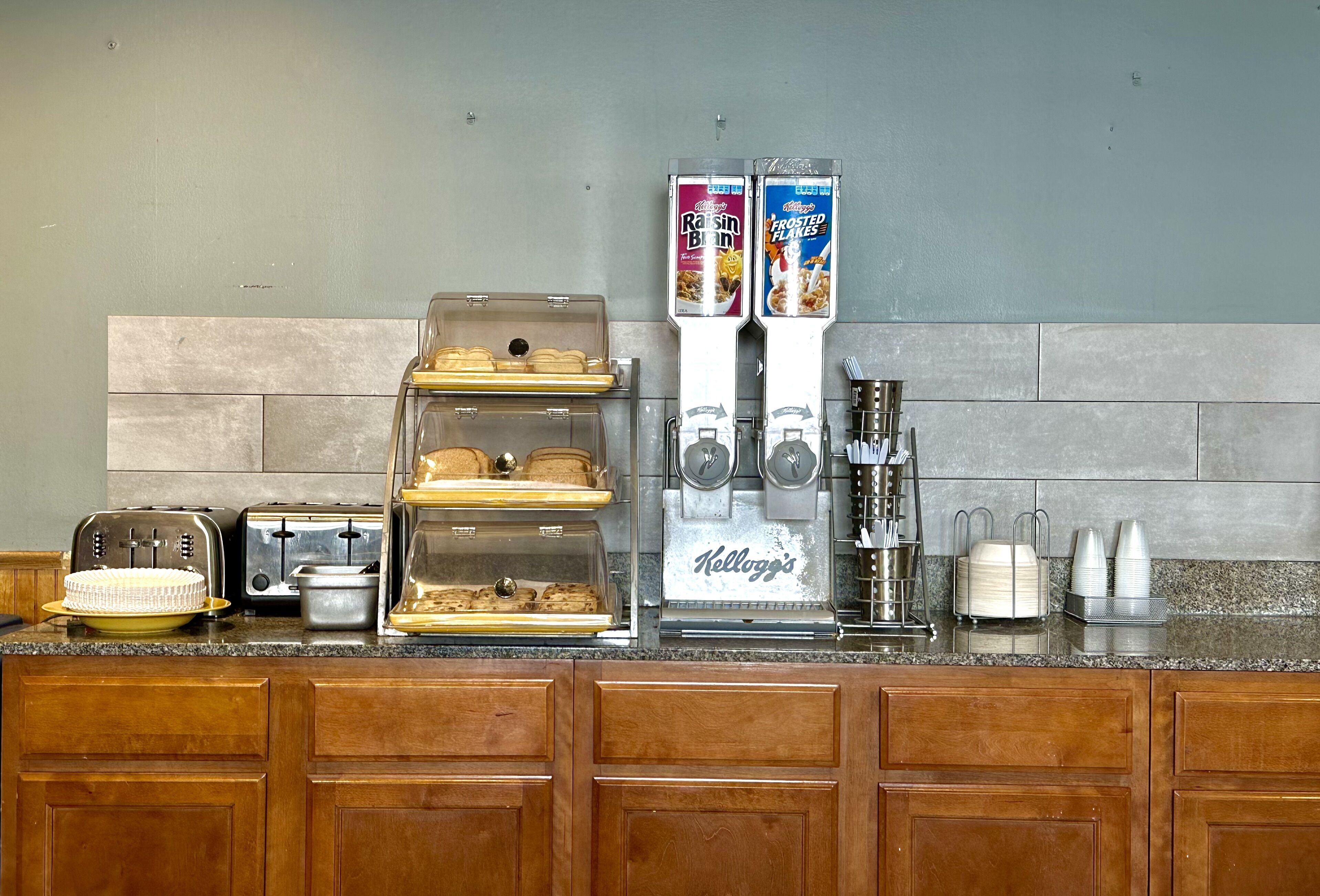 A breakfast bar with a coffee machine, toasters, and a display case with pastries.