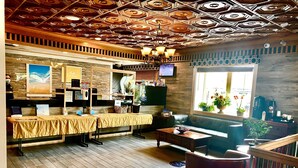 Rebedor d'hotel amb sòl de fusta, un sofà, una taula de centre i un televisor penjat a la paret.