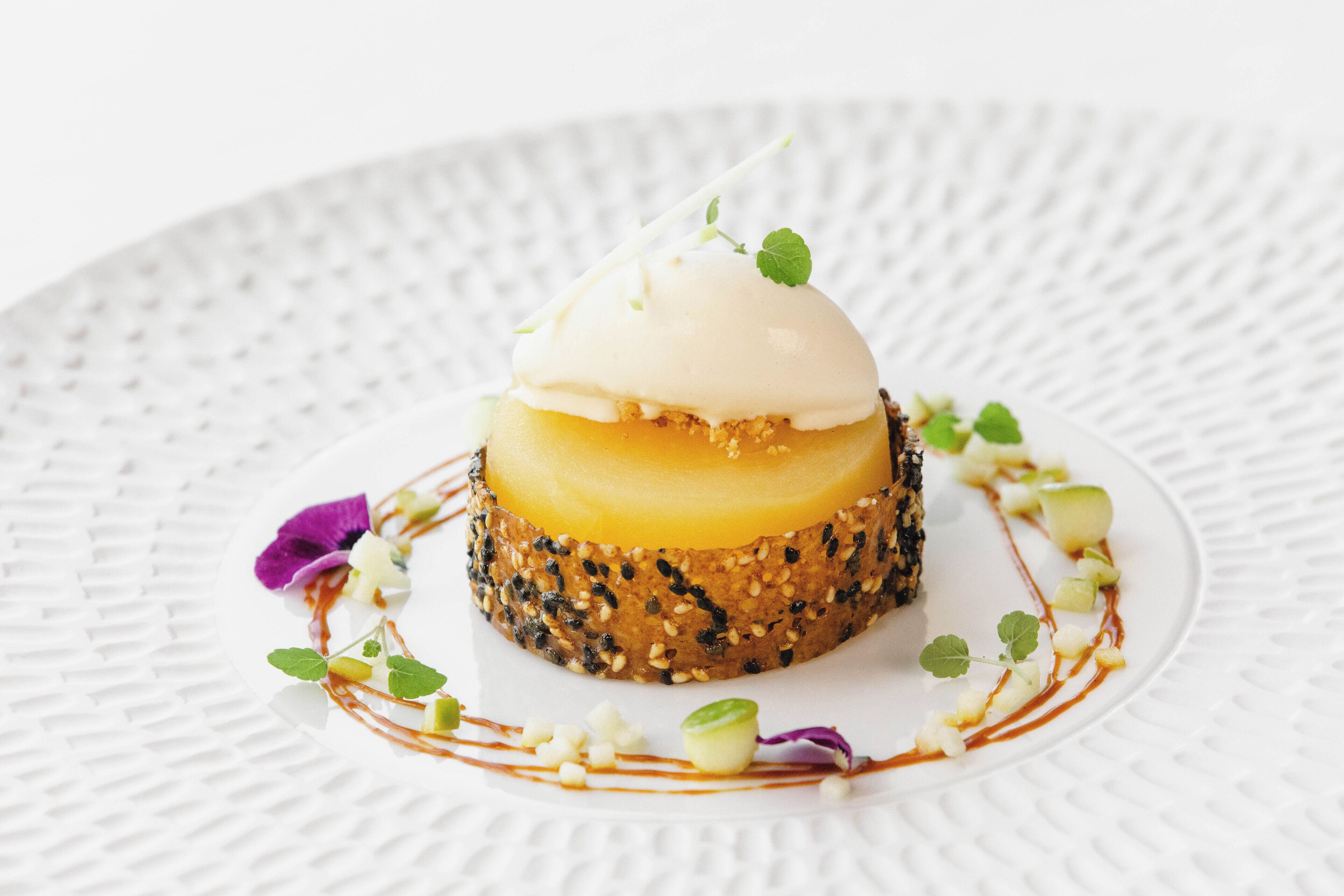 Un postre sobre un plato blanco con textura y una decoración.