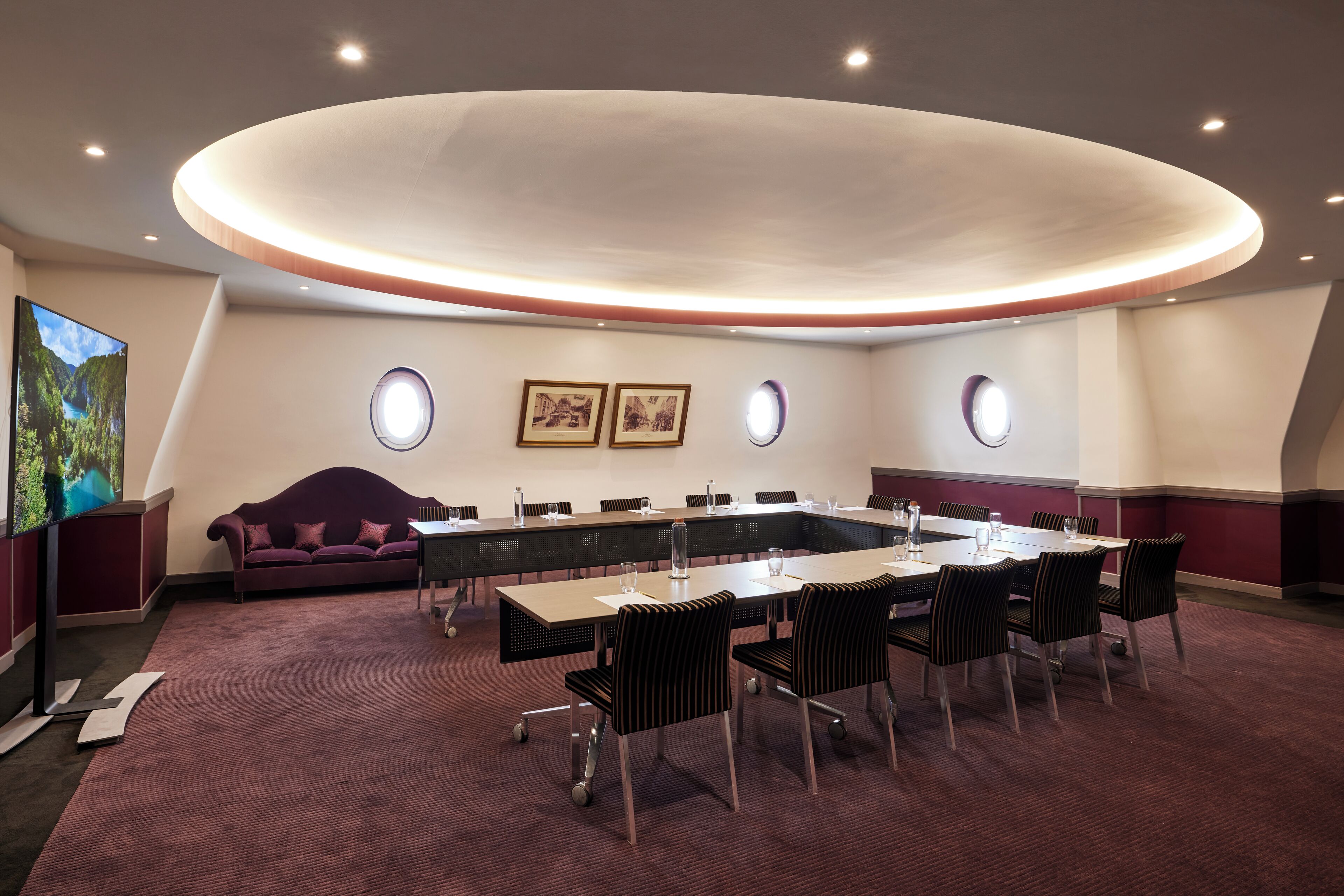 Uma sala de conferências com uma mesa comprida, cadeiras, um sofá e obras de arte nas paredes.
