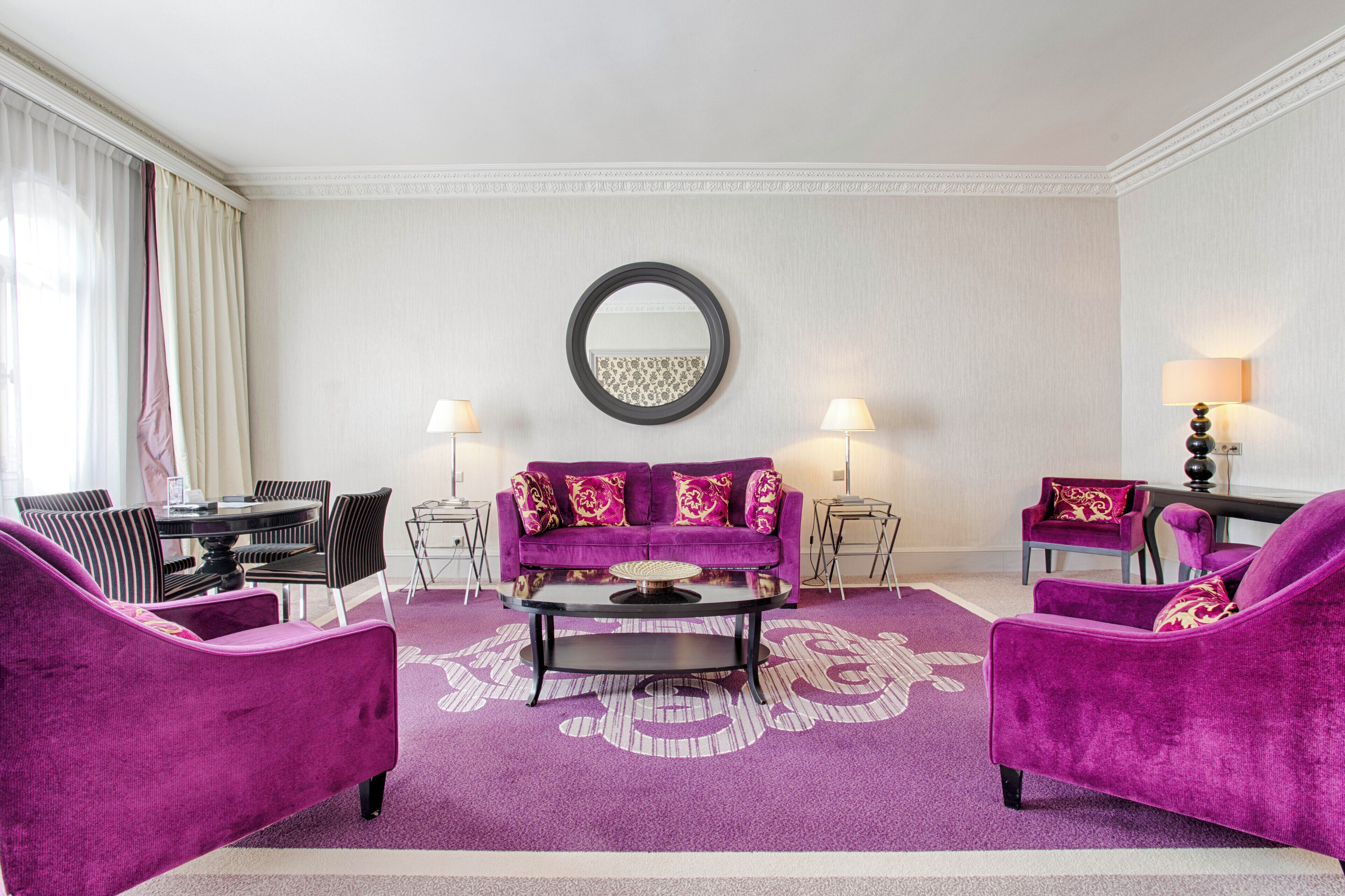 A living room with a purple sofa set, a round coffee table, and two side tables with lamps.