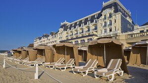 A hotel with multiple balconies and beach umbrellas. - Le Grand Hotel de Cabourg - MGallery Collection (Cabourg)