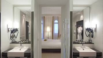 Een hotelbadkamer met twee wasbakken, een spiegel en een bed op de achtergrond.