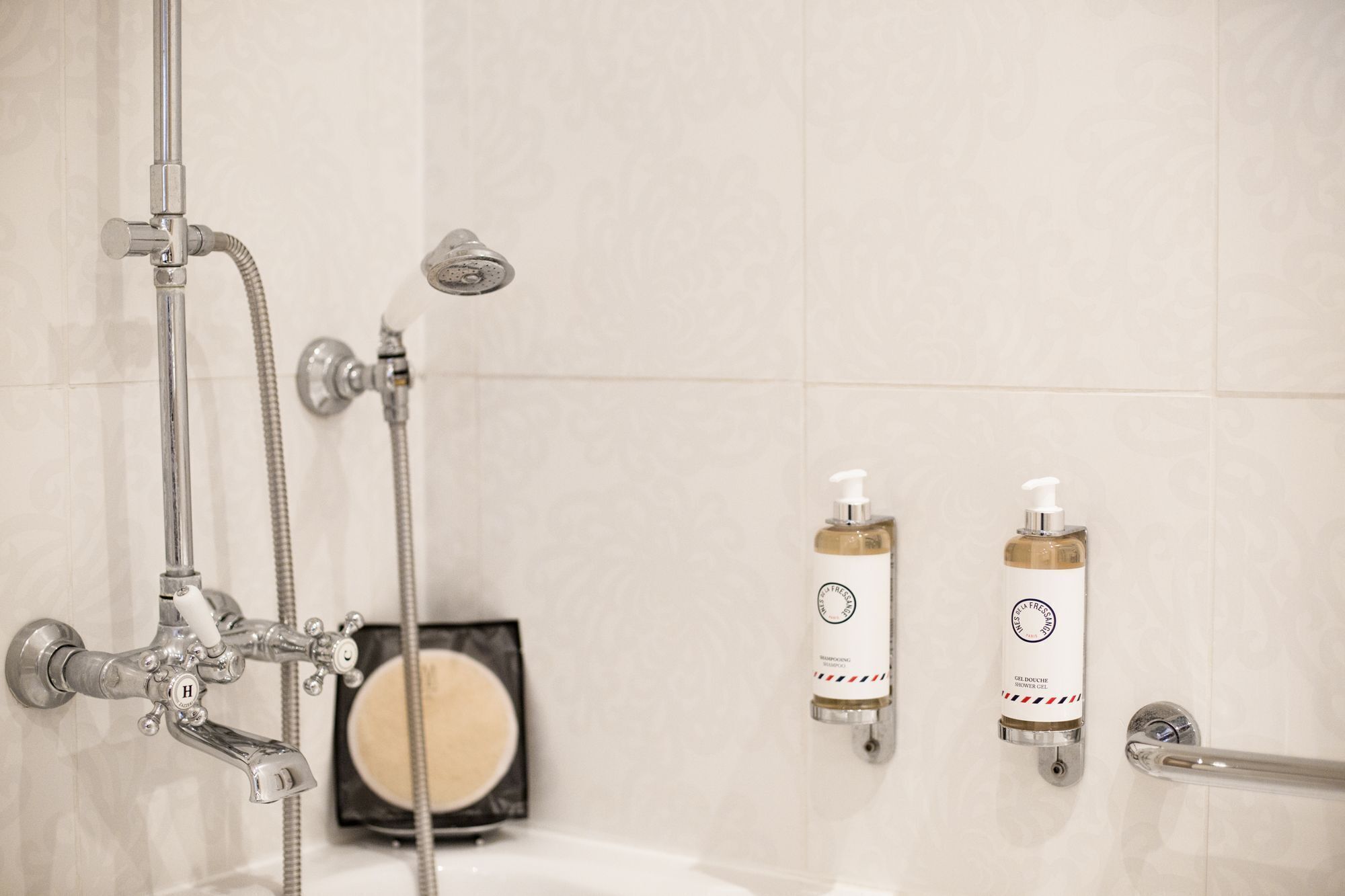 Une salle de bain avec une douche, deux flacons de gel douche et un porte-savon.