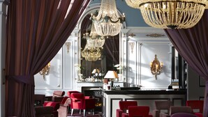 A luxurious interior with red upholstered chairs, a bar area, and ornate chandeliers. - Le Grand Hotel de Cabourg - MGallery Collection (Cabourg)