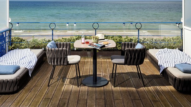 A deck with a table and chairs overlooking the sea. - Le Grand Hotel de Cabourg - MGallery Collection (Cabourg)