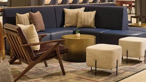 A modern living room with a sectional sofa, a coffee table, and a dining area in the background. - Sheraton Philadelphia University City Hotel (Philadelphia)