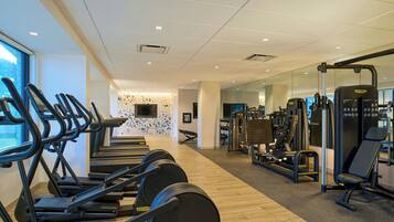 A gym with treadmills, weight machines, and a TV screen.