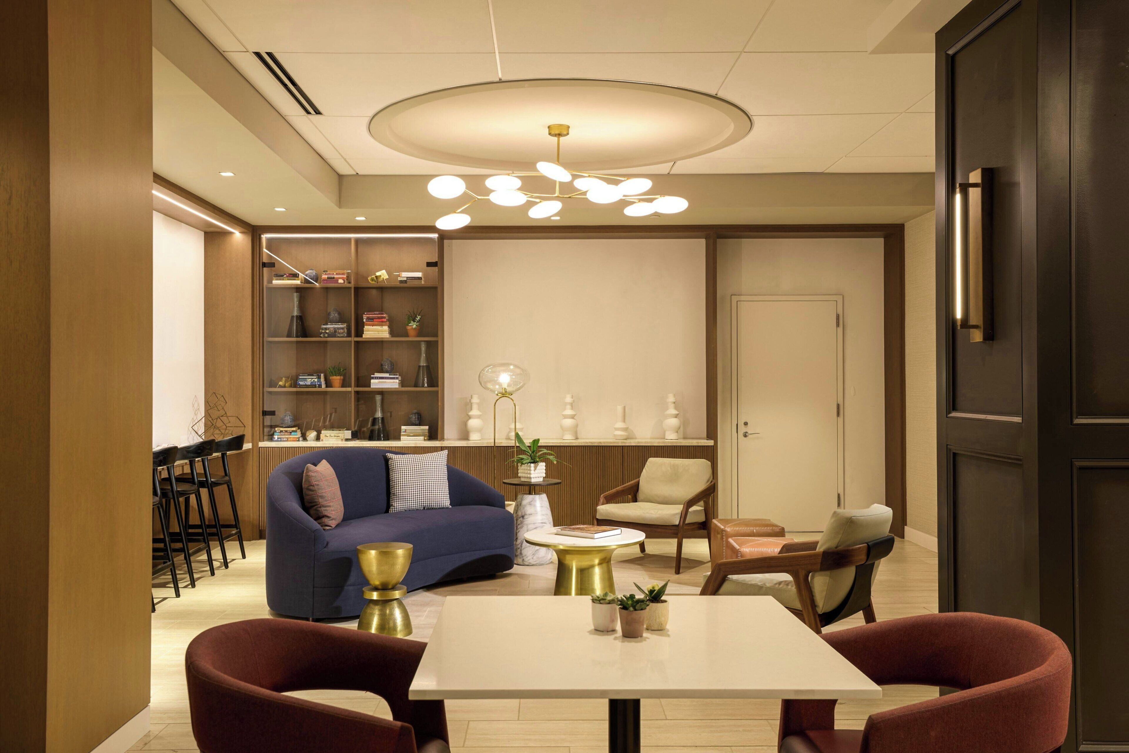A modern living room with a sofa, chairs, a table, and a bookshelf.