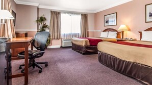 A hotel room with a bed, desk, chair, lamp, air conditioner, and a plant. - Econo Lodge Castro Valley I-580 (Castro Valley)