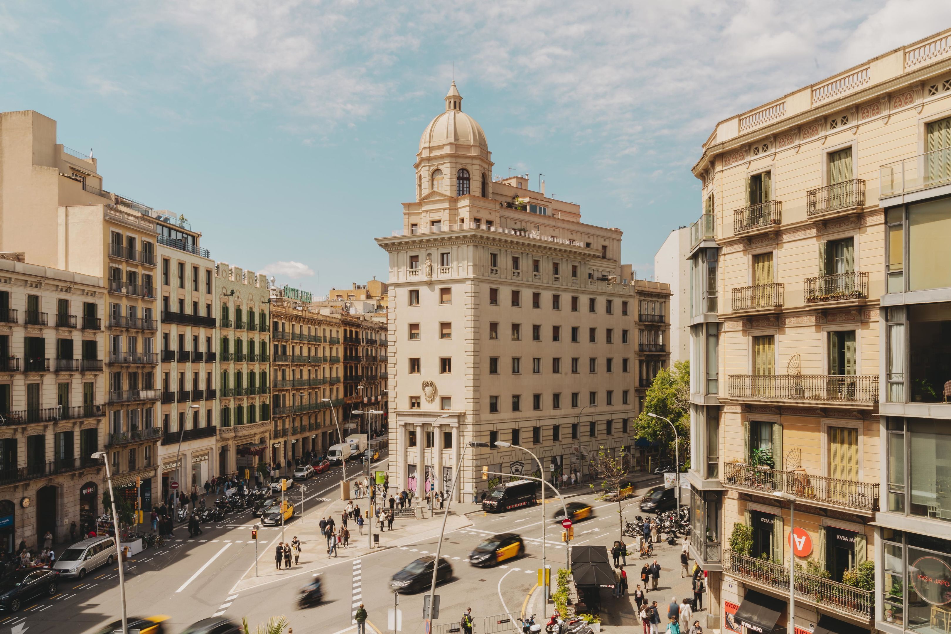 A busy urban street with historic buildings, including a prominent building with a dome and columns.