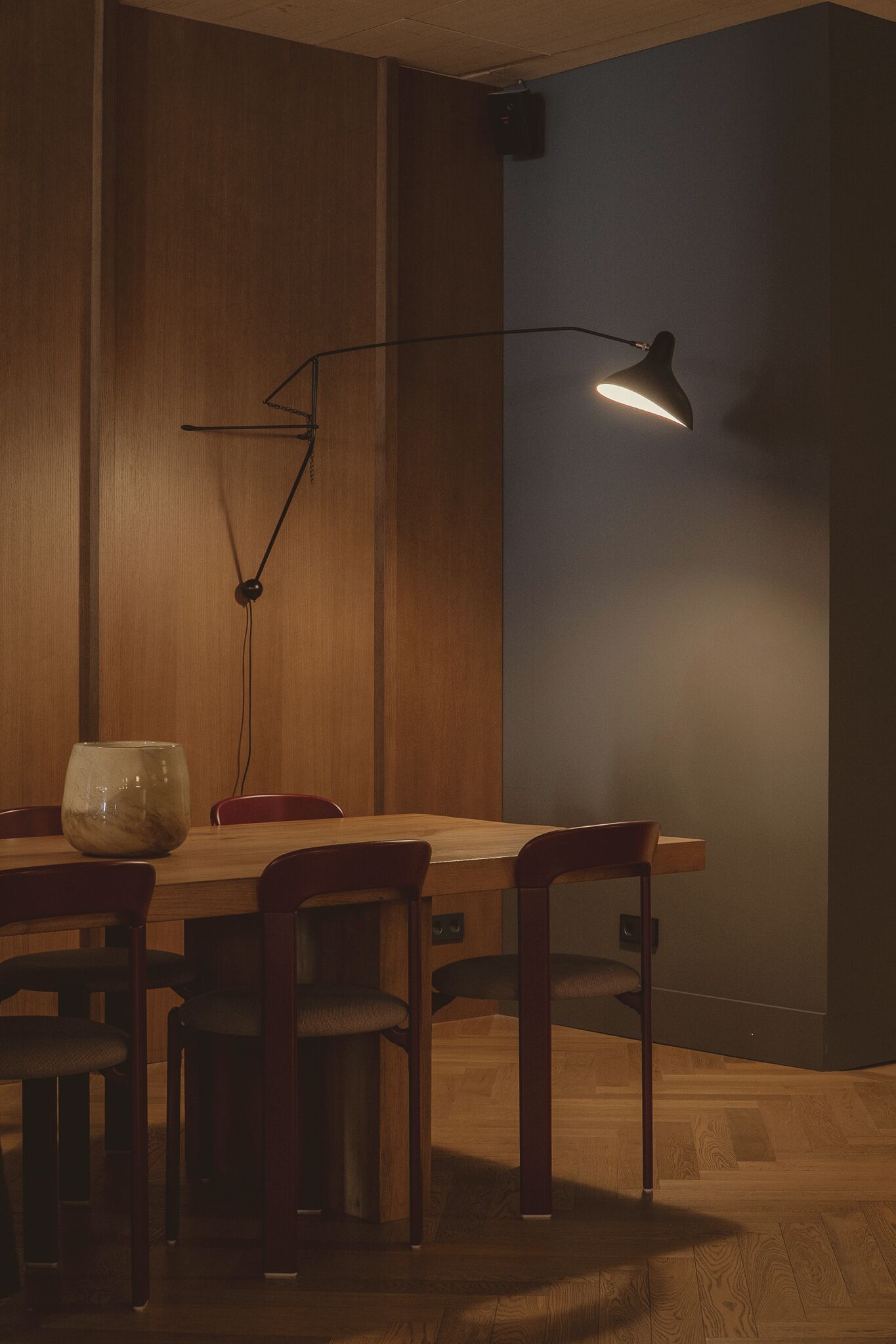 Een eethoek met een houten tafel en stoelen, een vaas en een hanglamp.