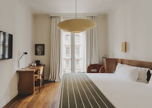 A hotel room with a bed, a desk, a chair, a television, and a window with curtains. - Hotel Regina Barcelona (Barcelona)