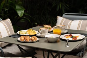 A breakfast table with croissants, scrambled eggs, bacon, and juice. - Hotel Regina Barcelona (Barcelona)