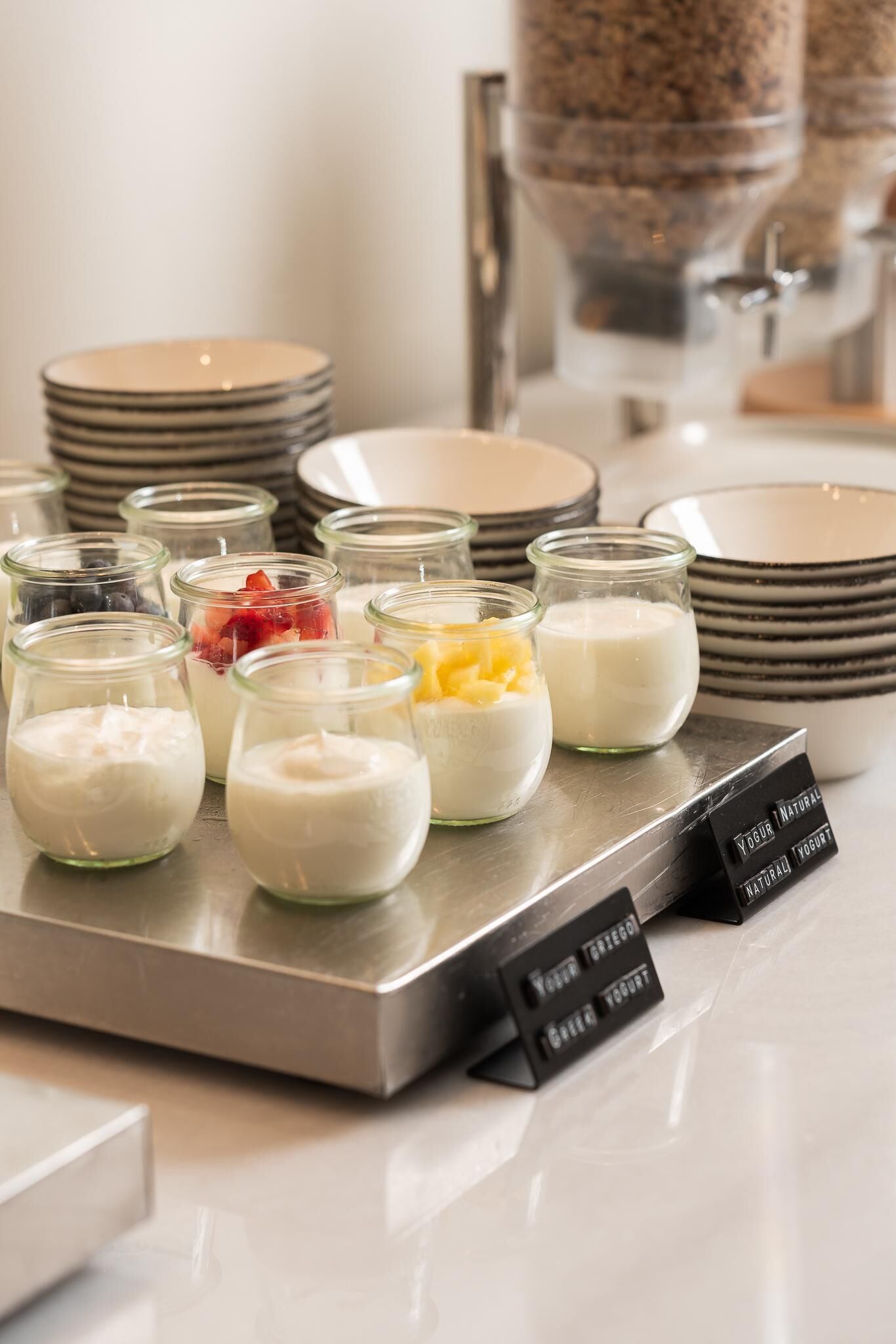 En buffet med forskellige yoghurt- og frugtsmoothies i små glas.