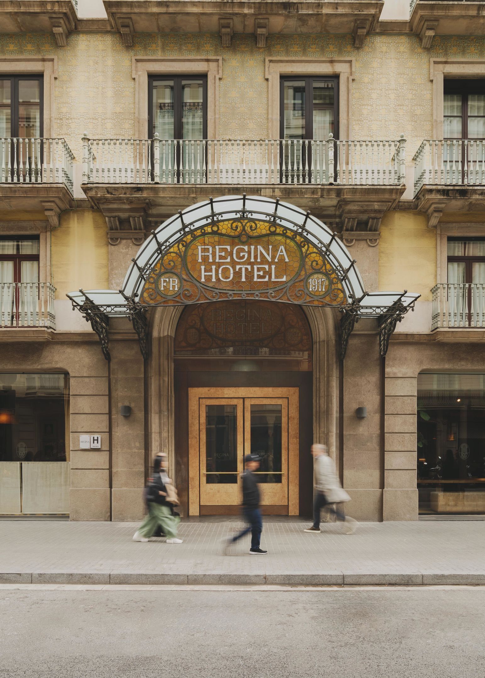 The facade of Regina Hotel with a classic architectural style, featuring a prominent entrance with a decorative arch and a signboard.