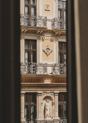 A building facade with ornate balconies, a central plaque, and a statue below the windows. - Hotel Regina Barcelona (Barcelona)