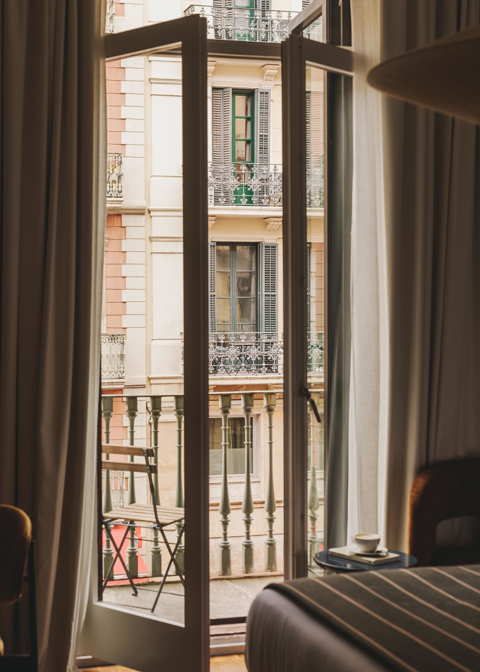 Un balcón abierto con vistas a un edificio con balcones y contraventanas.