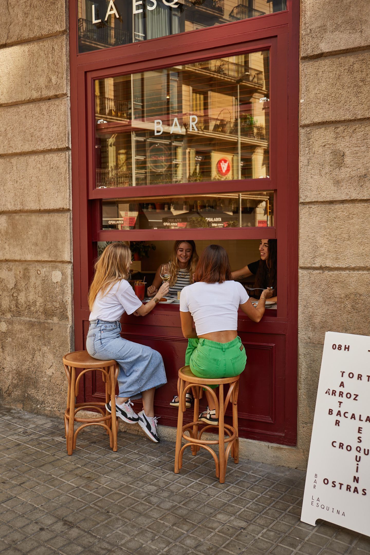 A bar with a red facade and a signboard listing menu items.
