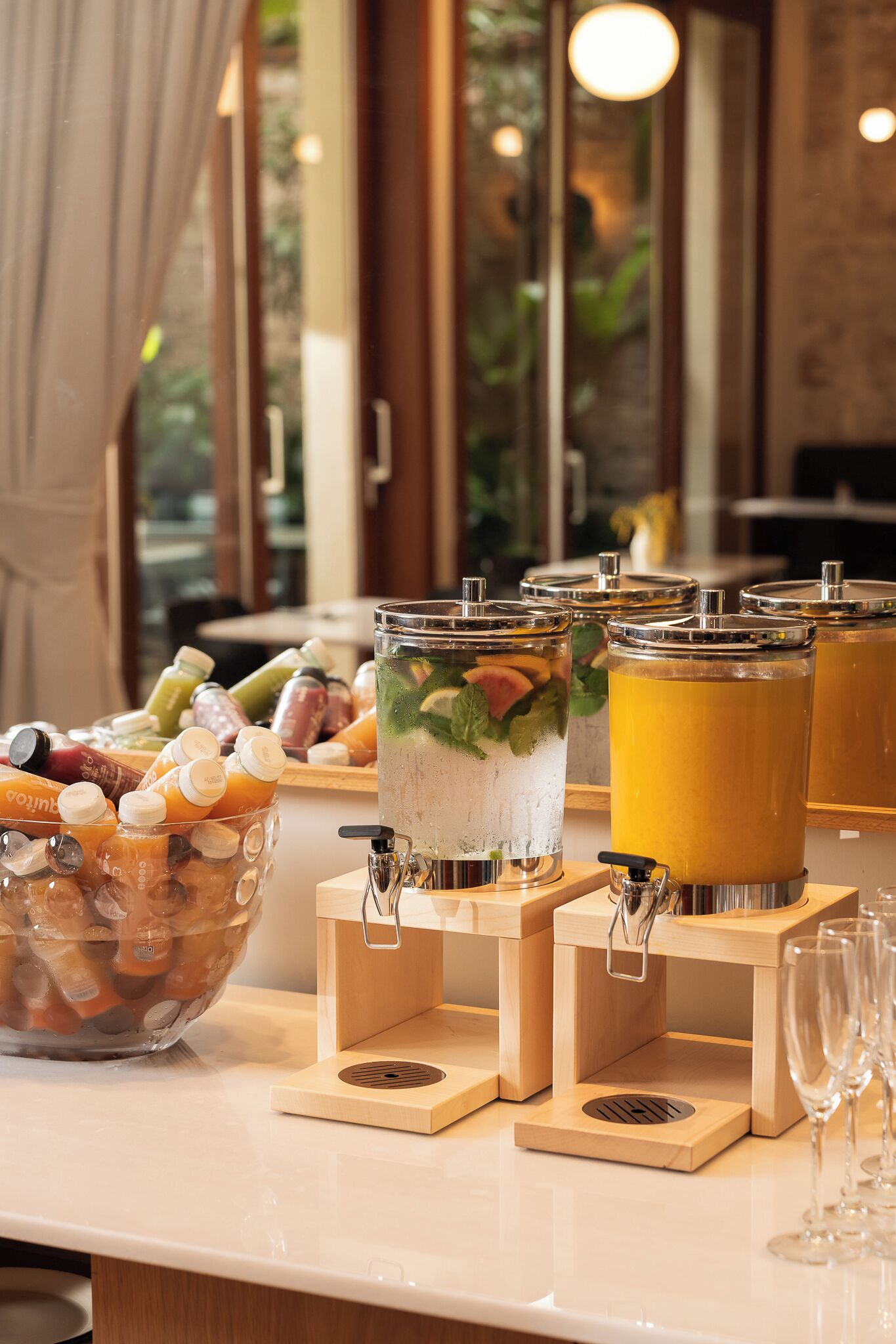 Uma área de bar com diversas bebidas, incluindo uma grande cesta de frutas e vários dispensadores.
