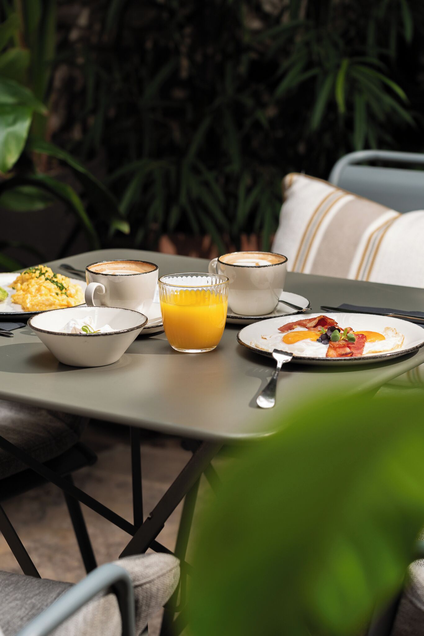 A table set with breakfast items including eggs, bacon, and toast, accompanied by a cup of coffee and a glass of orange juice.