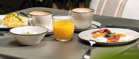 A table set with breakfast items including eggs, bacon, and toast, accompanied by a cup of coffee and a glass of orange juice.