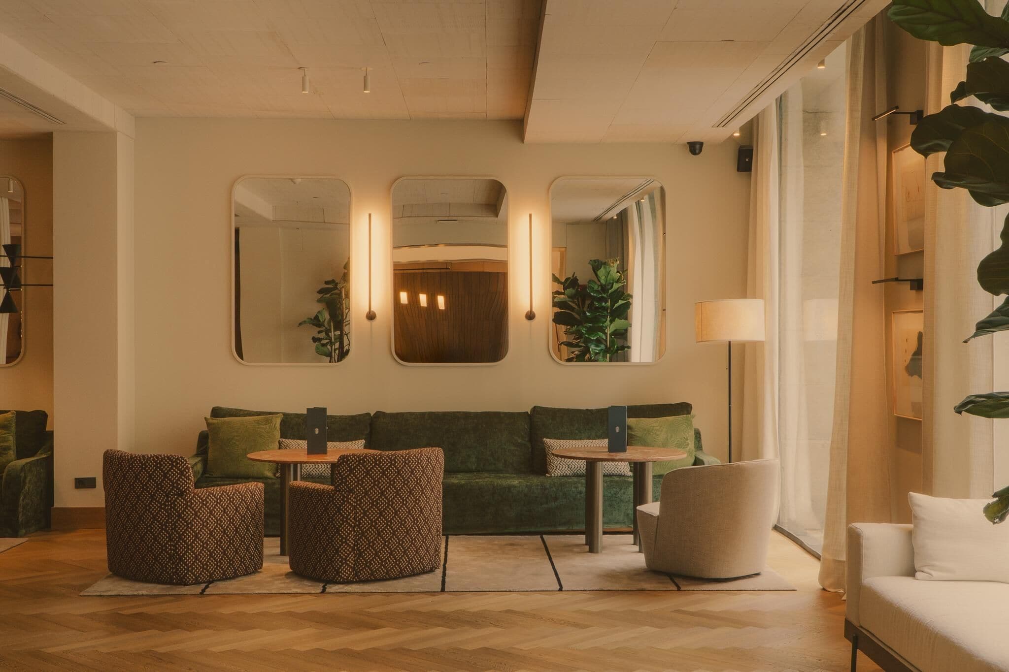 A modern living room with a green sofa, patterned ottomans, a small table, and a laptop.