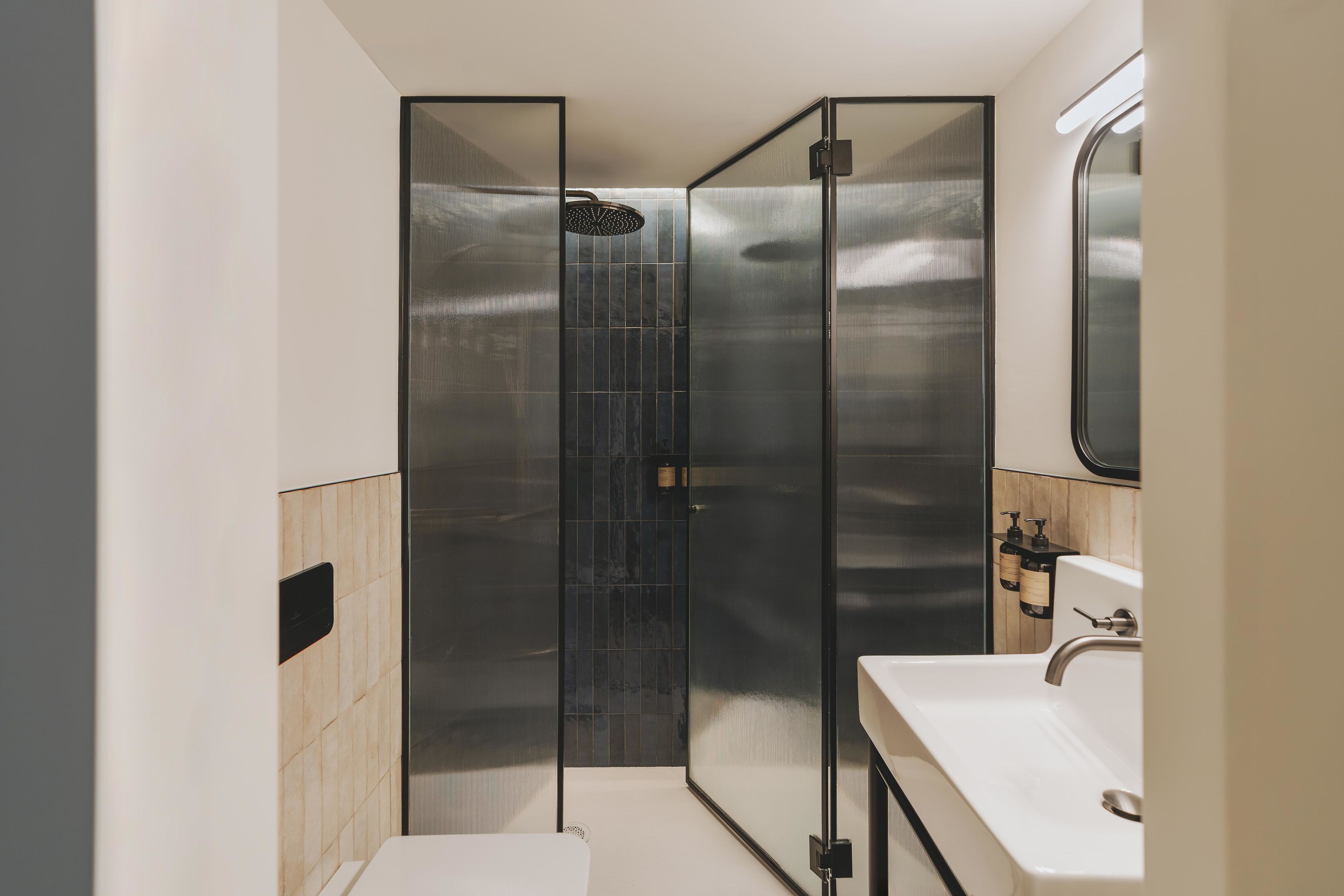 A modern bathroom with a glass-enclosed shower, a white sink, and a mirror above it.